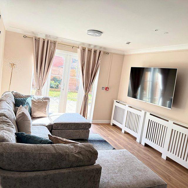 The television end of the living room, with soft seating facing a wall-mounted screen.